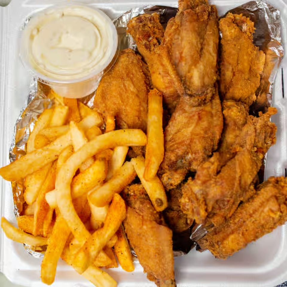 Dale's Deli fried chicken wings and french fries with a side of dipping sauce.