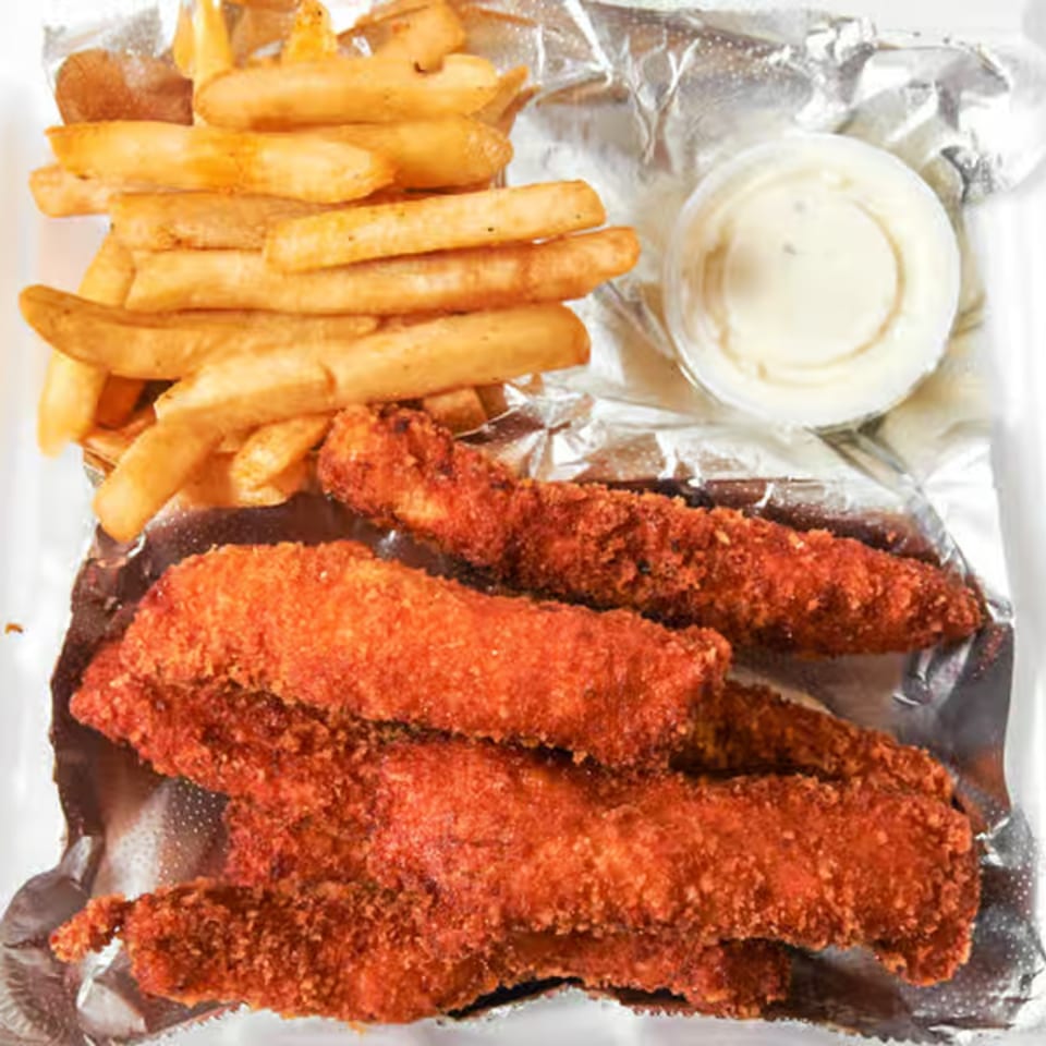 Crispy chicken tenders, golden french fries, and a side of dipping sauce in a foil container.